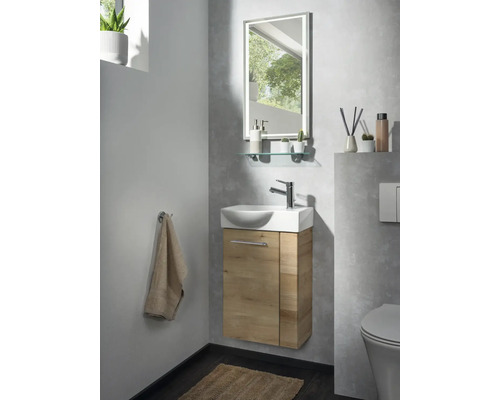 Salle de bains d'invités moderne avec petit lavabo, meuble sous-vasque aspect bois, robinet chromé et miroir éclairé.