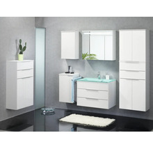 Ensemble de meubles de salle de bains blanc avec vasque en verre vert, armoire de toilette éclairée et plusieurs armoires suspendues.