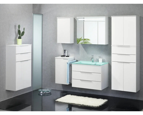 Ensemble de meubles de salle de bains blanc avec vasque en verre vert, armoire de toilette éclairée et plusieurs armoires suspendues.