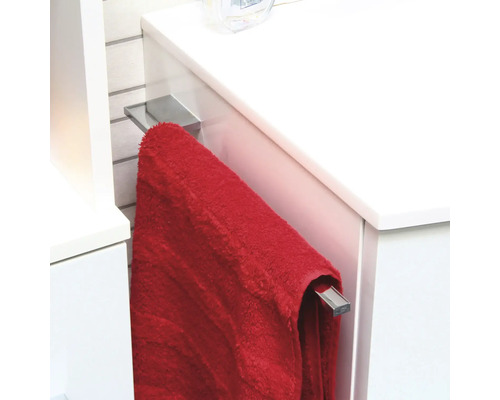 Porte-serviettes en métal chromé, monté latéralement sur un meuble sous-lavabo blanc avec une serviette rouge.