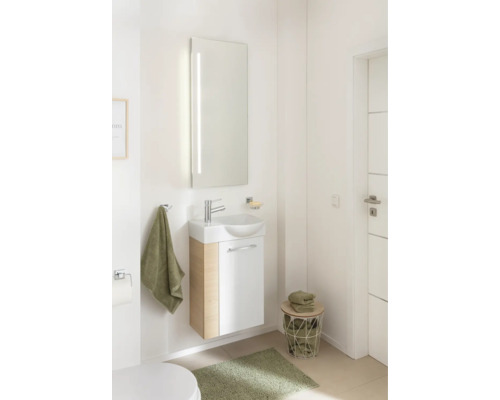 Ensemble de toilettes d'invités moderne avec meuble sous-lavabo aspect bois, lavabo en céramique et grand miroir éclairé dans une salle de bain.