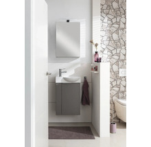 Ensemble de toilettes pour invités moderne avec meuble sous lavabo gris, lavabo blanc, miroir avec éclairage et mur en pierre naturelle.