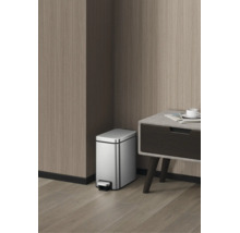 Poubelle à pédale rectangulaire en acier inoxydable dans une pièce moderne avec des parois en bois à côté d'une table.