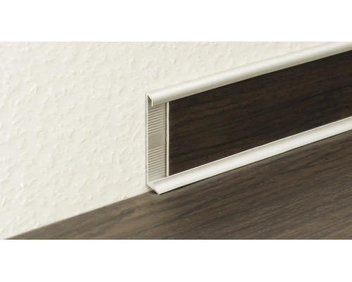 Profilé de plinthe en métal argenté avec insert aspect bois foncé à la jonction du mur et du sol.