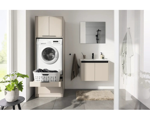 Salle de bains lumineuse avec armoire pour lave-linge beige, lave-linge, tablette coulissante pour panier à linge et meuble sous-vasque assorti.