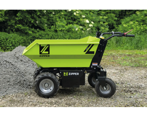 Dumper électrique Zipper avec grande benne et quatre roues sur du gravier à côté d'un tas de pierres.