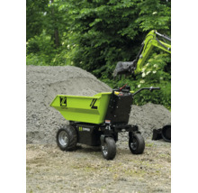 Brouette électrique Zipper sur un chantier à côté d'un tas de sable et d'un bras de pelle.