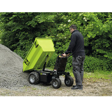 Un homme vide un dumper motorisé Zipper avec mécanisme de basculement sur un tas de gravier. Environnement extérieur fonctionnel. Zipper Logo.