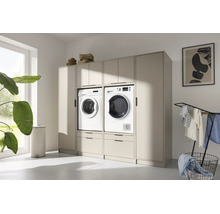 Meuble de buanderie beige moderne avec lave-linge et sèche-linge intégrés, tiroirs et placards supérieurs dans une pièce lumineuse.