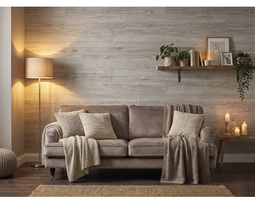 Salon avec des panneaux muraux en aspect bois, un canapé avec des coussins et des couvertures, un lampadaire et une étagère murale.
