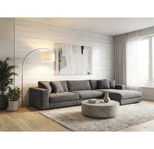Salon lumineux avec canapé d'angle gris, table basse ronde, lampadaire arqué et mur en bois blanc. Style moderne avec parquet et tapis.