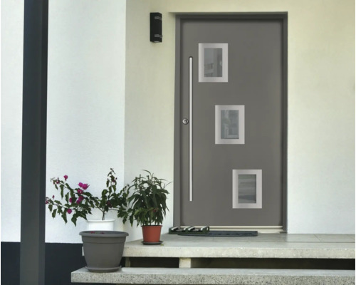 Moderne graue Haustür mit drei quadratischen Lichtausschnitten und langem Stoßgriff aus Edelstahl in einer hellen Fassade mit Topfpflanzen.