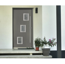 Porte d'entrée moderne grise avec trois ouvertures carrées vitrées et une longue poignée en acier inoxydable devant une façade blanche.
