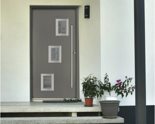 Porte d'entrée moderne grise avec trois ouvertures carrées vitrées et une longue poignée en acier inoxydable devant une façade blanche.