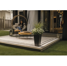 Terrasse moderne avec tapis d'extérieur, tables en bois rondes, un fauteuil suspendu et un pot de fleurs haut avec des fleurs et des herbes.