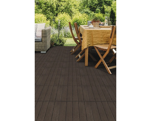 Dunkle WPC Terrassenfliesen auf einer hellen Gartenterrasse mit Esstisch, Holzstühlen und Lounge-Sessel im grünen Außenbereich.