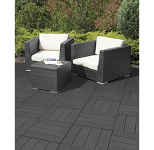 Terrasse avec dalles clipsables en bois composite anthracite, deux fauteuils en résine tressée avec coussins clairs et une table basse.