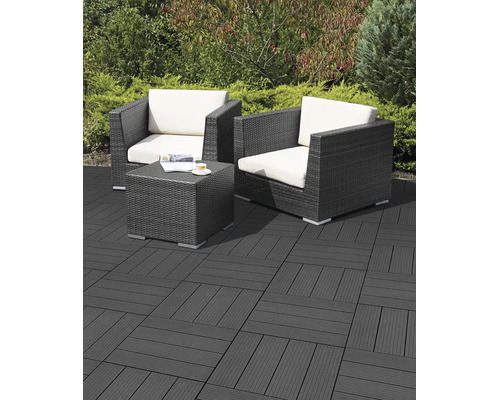 Terrasse avec dalles clipsables en bois composite anthracite, deux fauteuils en résine tressée avec coussins clairs et une table basse.
