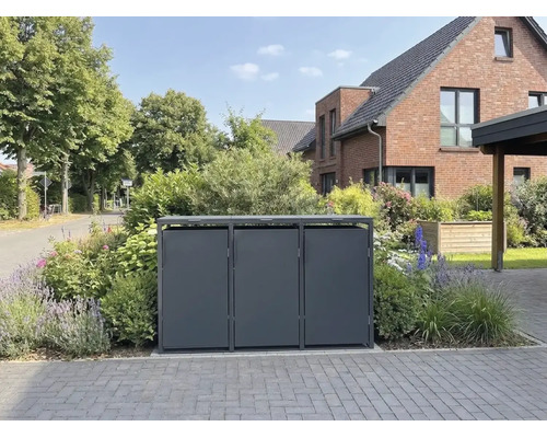 Abri triple moderne pour poubelles en métal dans un jardin devant une maison en briques.