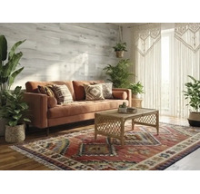 Salon lumineux de style boho avec canapé en velours, table basse en rotin et tapis à motifs. Plantes vertes et panneaux muraux en bois.