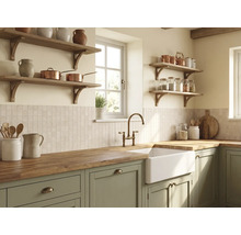 Cuisine rustique lumineuse avec meubles vert sauge, plan de travail en bois massif, évier timbre d'office blanc, robinet en laiton et étagères.