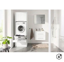 Weißer Waschmaschinenschrank im hellen Badezimmer mit Auszug für Wäschekorb, Oberschrank und Waschbecken daneben. (Image AI modified or generated)