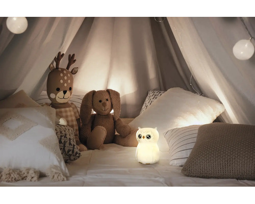 Leuchtendes Nachtlicht in Eulenform in einem Kinderzelt mit Stofftieren und Kissen.