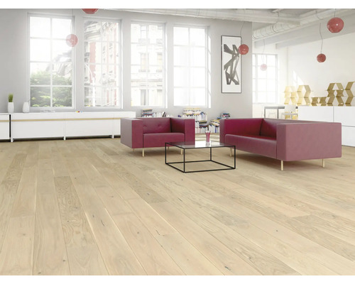 Espace de vie lumineux avec parquet en bois clair, canapés rouges, table basse en verre et grandes fenêtres dans un style loft.