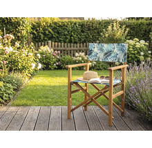 Chaise de metteur en scène en bois avec motif de feuilles tropicales sur une terrasse de jardin avec chapeau de paille et livre.