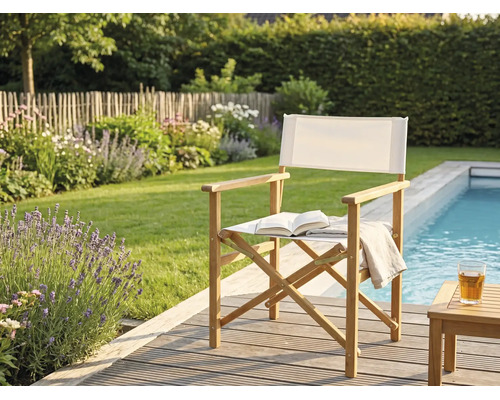 Klappstuhl aus Holz mit weißem Stoffbezug auf einer Holzterrasse am Pool im Garten.