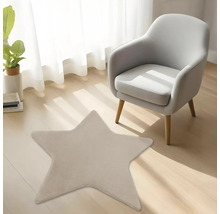 Tapis en peluche en forme d'étoile sur un sol en bois clair dans une pièce lumineuse à côté d'un fauteuil gris moderne.