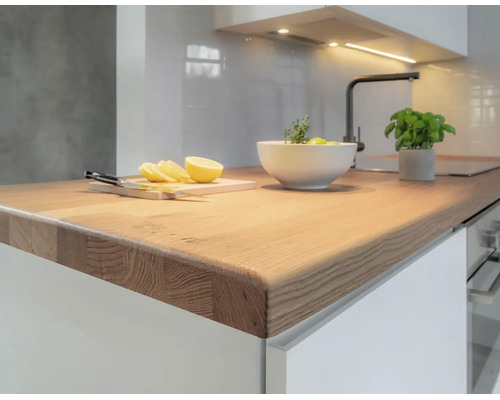 Cuisine moderne avec un plan de travail en bois massif, des meubles et un robinet. Espace de travail lumineux et organisé.