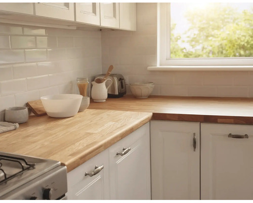 Cuisine lumineuse avec plan de travail en bois massif, meubles blancs et carrelage métro blanc. Comprend une fenêtre, un grille-pain et des bols.