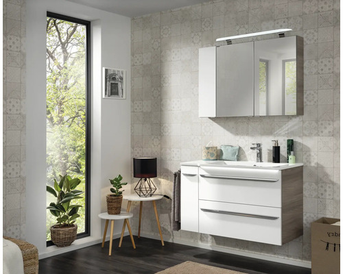 Salle de bain moderne avec meuble sous-vasque blanc et bois, lavabo et armoire de toilette à trois portes avec éclairage LED.