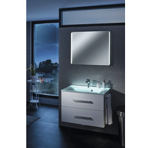Modern beleuchteter Waschplatz mit weißem Unterschrank, Glaswaschtisch und Spiegel in einem Badezimmer mit Ausblick auf eine nächtliche Stadt.