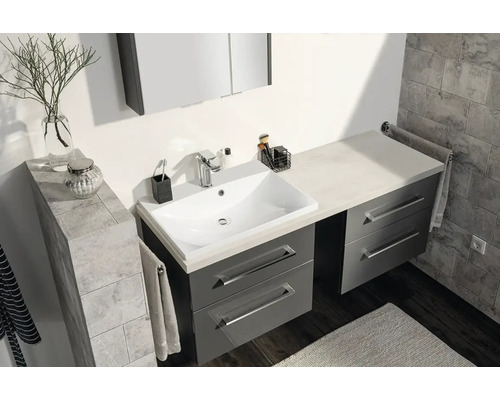 Salle de bains moderne avec meuble sous-lavabo gris, lavabo blanc et armoire de toilette sur fond de carrelage gris.