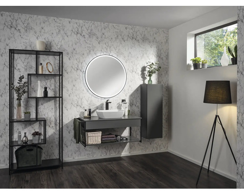 Salle de bains moderne avec papier peint aspect marbre, meuble gris foncé avec vasque à poser, miroir rond lumineux et étagère noire.