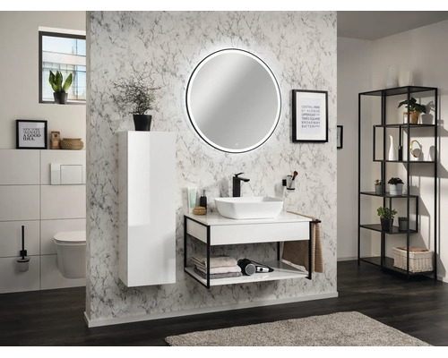 Salle de bain moderne avec meuble sous-vasque blanc, cadre noir, vasque à poser, miroir LED rond et armoire haute blanche devant un mur de marbre.
