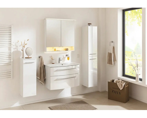 Ensemble de meubles de salle de bains blancs avec lavabo, armoire de toilette et deux armoires latérales dans une pièce lumineuse.