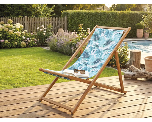 Liegestuhl aus Holz mit tropischem Blattmuster auf einer Holzterrasse im Garten neben einem Pool.