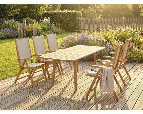 Ensemble de meubles de jardin en bois avec une table rectangulaire et cinq chaises pliantes sur une terrasse en bois dans un jardin ensoleillé.