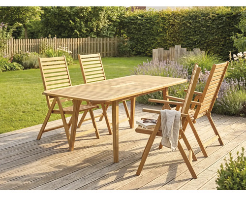 Salon de jardin en bois avec table rectangulaire et quatre chaises pliantes sur une terrasse en bois dans un jardin.