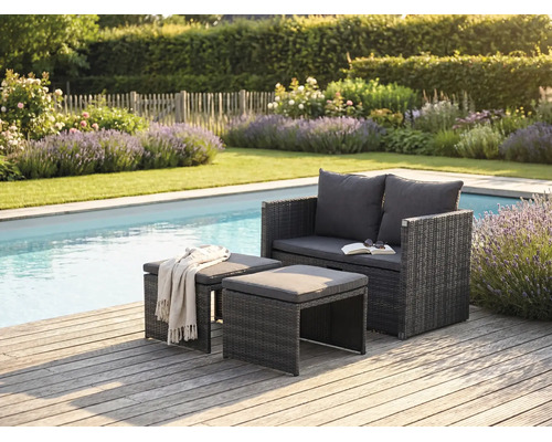 Moderne Gartenlounge aus Polyrattan mit Sofa und zwei Hockern auf einer Holzterrasse am Pool in einem hellen, gepflegten Garten.
