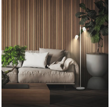 Scène de salon moderne avec un lampadaire à deux spots à côté d'un canapé devant un mur en lattes de bois et une grande plante d'intérieur.