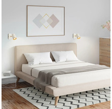 Chambre à coucher moderne avec lit double, tête de lit rembourrée beige et deux appliques murales blanches au-dessus du lit.