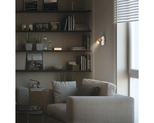Applique murale moderne avec abat-jour en bois dans un salon chaleureux avec canapé, étagères et éclairage doux.