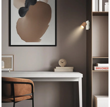 Espace de travail moderne avec un bureau blanc, une chaise marron et une étagère. Une applique murale en bois éclaire la pièce minimaliste.