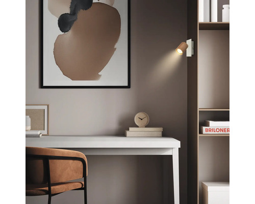 Espace de travail moderne avec un bureau blanc, une chaise marron et une étagère. Une applique murale en bois éclaire la pièce minimaliste.