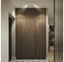 Armoire encastrée moderne en aspect bois avec trois portes et spots de plafond dans un couloir lumineux avec des carreaux de sol à motifs.