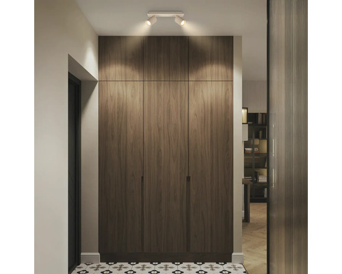 Armoire encastrée moderne en aspect bois avec trois portes et spots de plafond dans un couloir lumineux avec des carreaux de sol à motifs.
